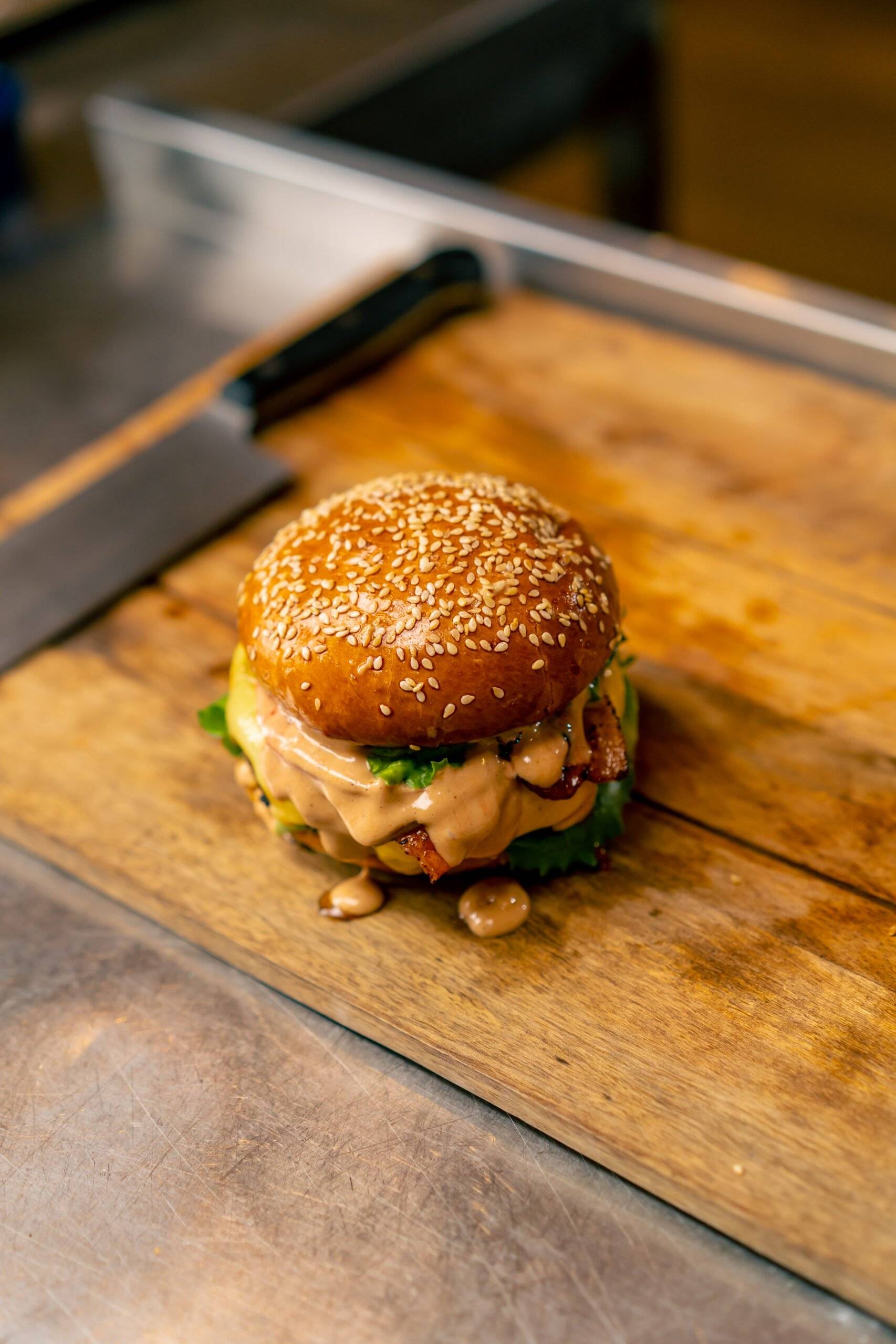 a close up of a burger with beef patty with vegetables and cheese cooked in the professional kitchen of an italian restaurant